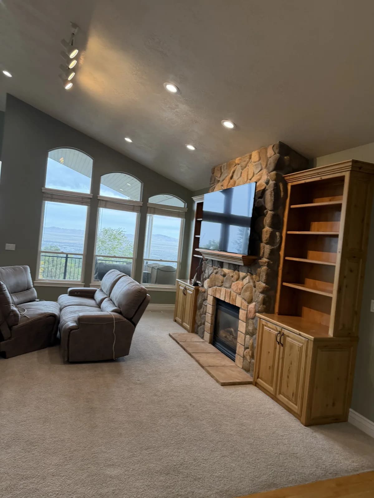 Vaulted great room in a Bountiful bench home with freshly painted sage walls, a stone fireplace, and valley views