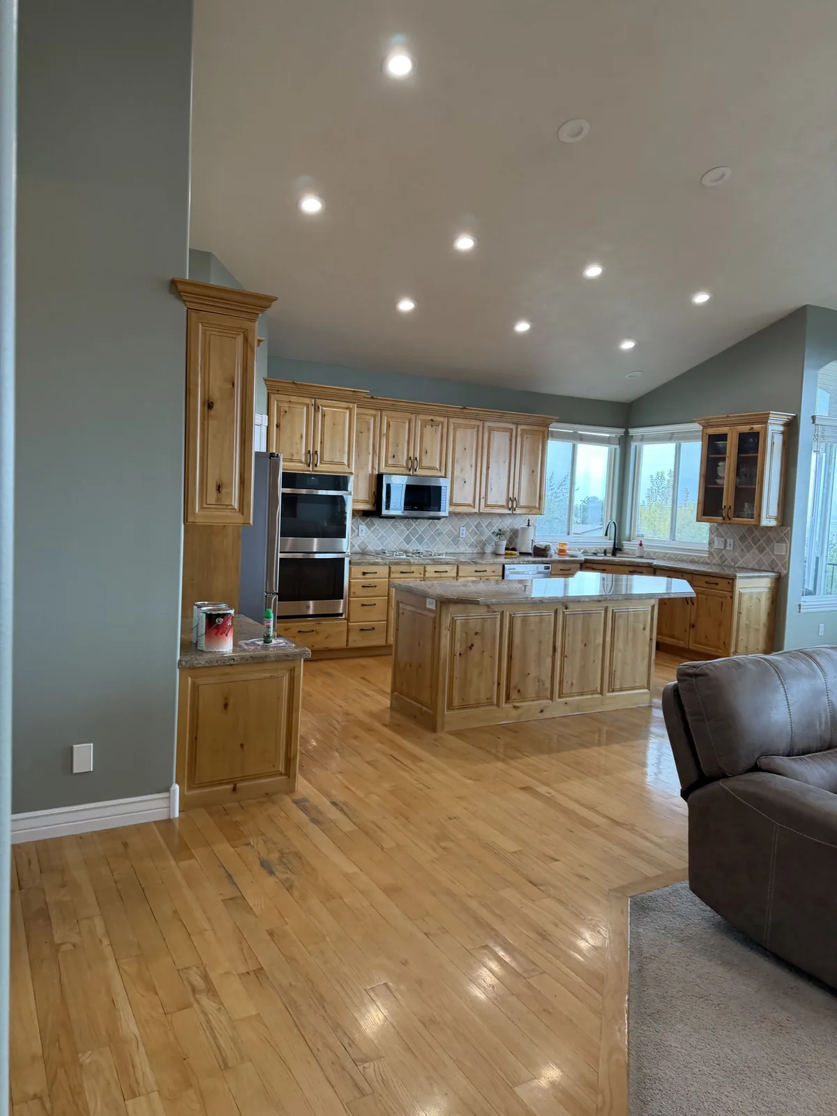 Open kitchen in a Bountiful home with freshly painted sage-green walls and knotty alder cabinets