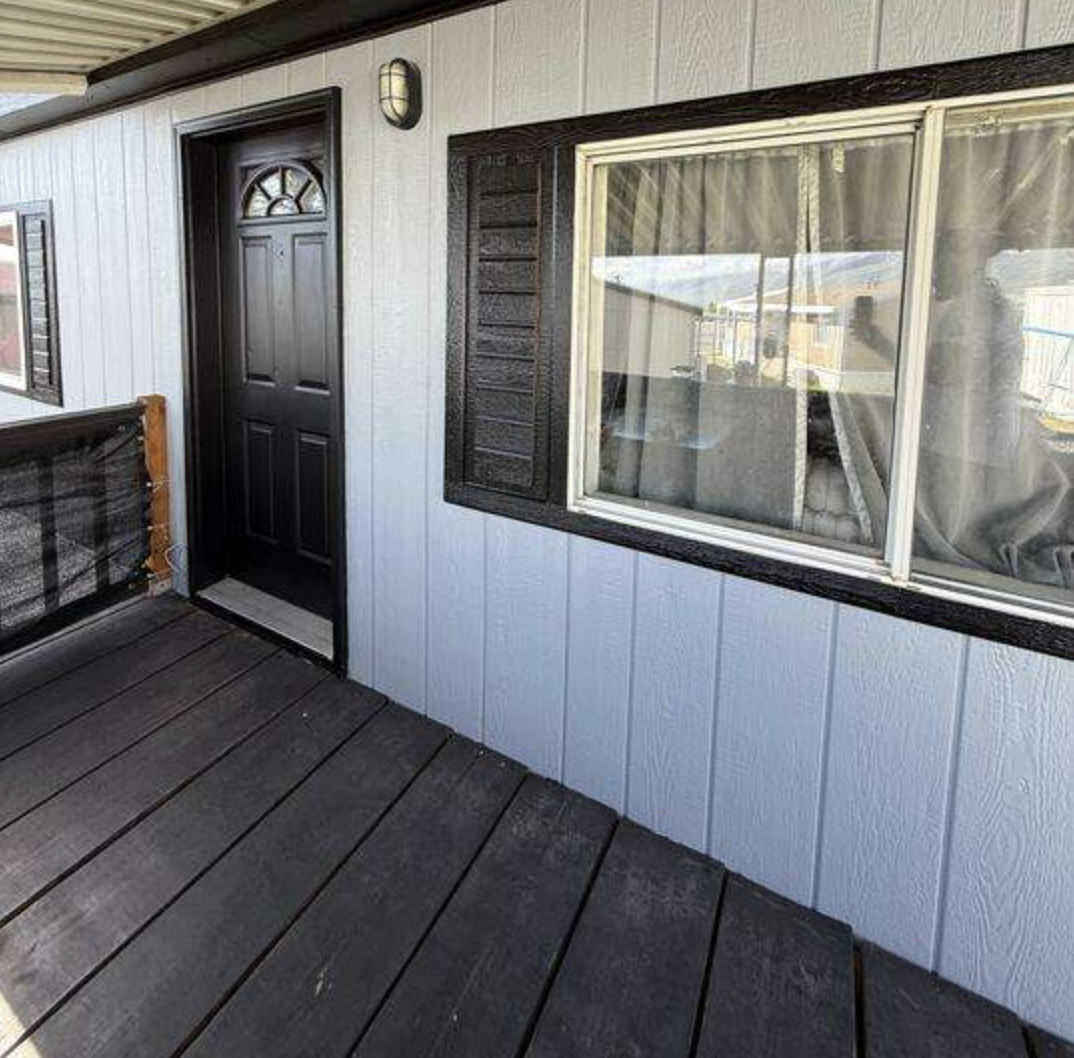 Freshly painted Utah home exterior with board-and-batten siding, dark trim, and stained porch decking