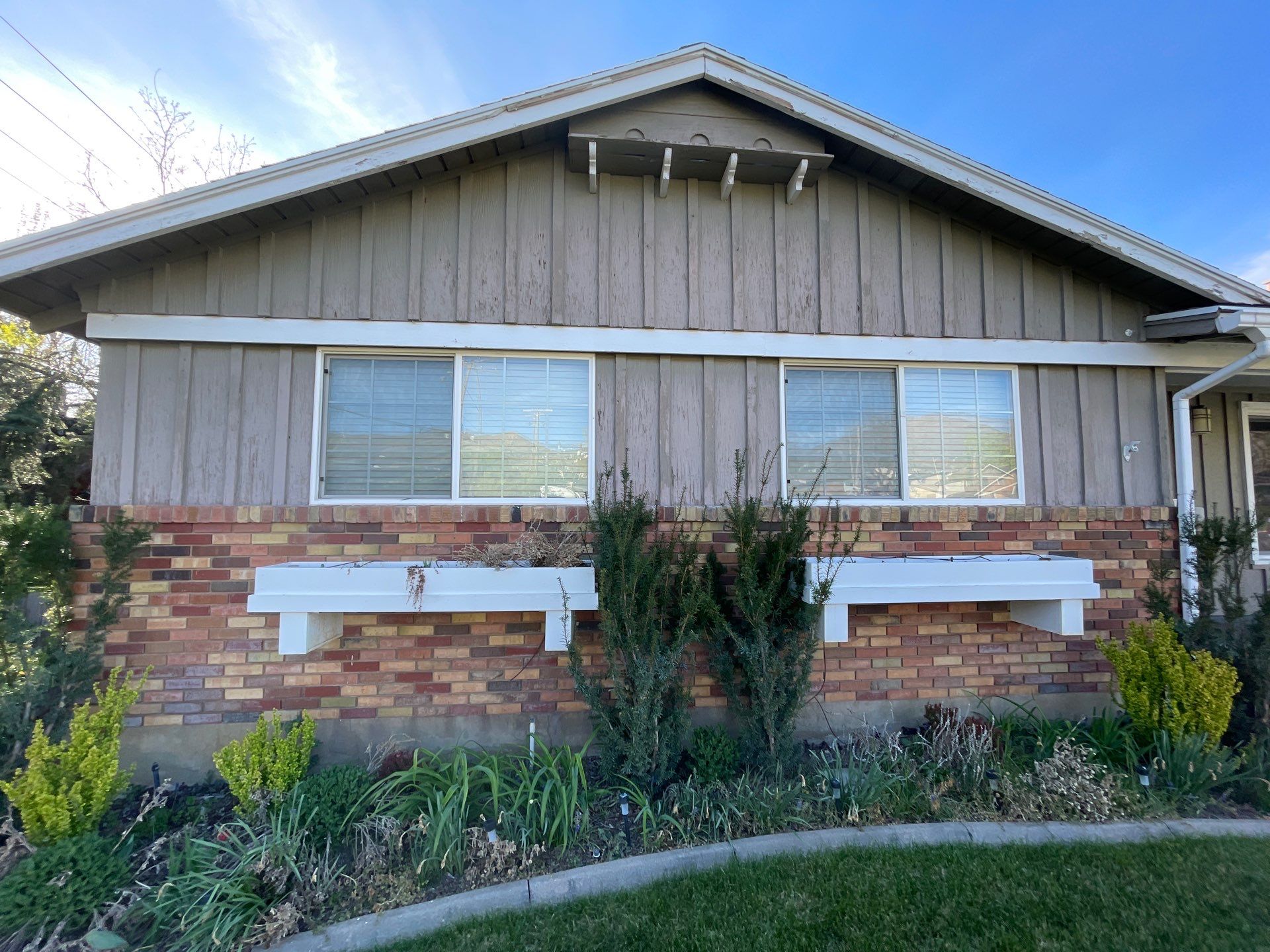 Older Bountiful rambler with brick lower facade and weathered wood siding before exterior painting