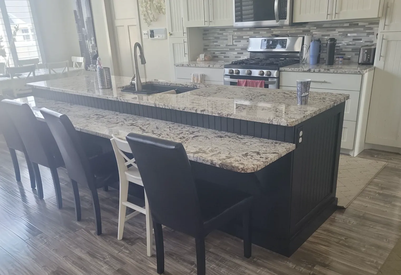 Kitchen with professionally painted dark island cabinets and reinstalled hardware